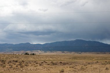 Karanlık bulutlu gökyüzü ve toprak kuru ot ile yaz yatay dağ. Dağlarda fırtına öncesi sessizlik. Elektrik için gergin teller ile ayağı vardır.