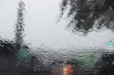 Su cam büyük bir duş sırasında çalışır. Bir araba arabalar geçme arka planı cama su akar.