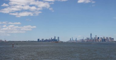 Ufukta New York gökdelenleri görülüyor. New York gökdelenleri uzakta. Bay, mavi gökyüzü, New York'ta güneşli yaz günü.