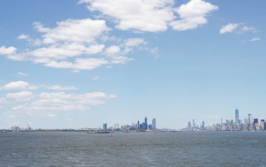 Ufukta New York gökdelenleri görülüyor. New York gökdelenleri uzakta. Bay, mavi gökyüzü, New York'ta güneşli yaz günü.