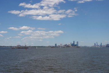 Ufukta New York gökdelenleri görülüyor. New York gökdelenleri uzakta. Bay, mavi gökyüzü, New York'ta güneşli yaz günü.