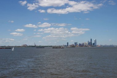 Ufukta New York gökdelenleri görülüyor. New York gökdelenleri uzakta. Bay, mavi gökyüzü, New York'ta güneşli yaz günü.