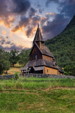 A stunning view of the Borgund Stave Church in Norway, a prime example of traditional wooden architecture, standing proudly against a backdrop of lush green hills. This church, built in the 12th century, is a testament to the craftsmanship and religi