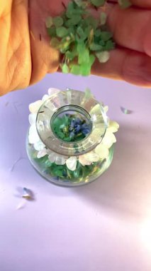 Ham koyu kristal, gül kuvars bileziği ve lavanta arkaplanındaki cam vazoda kurumuş çiçekler iyileşmeyi, kendini sevmeyi ve doğayla mistik bir bağı sembolize ediyor..