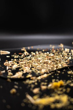 Koyu bir yüzeyde, kurumuş yaprakları ve kökleri toprak tonlarında gösteren, iyiliği, doğal çareleri ve geleneksel çay karışımlarını sembolize eden gevşek yapraklı bitki çayının yakın çekimi..