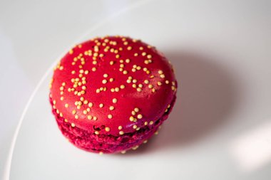 Beyaz çiçek kaplamalı renkli badem kurabiyeleri ve sıcak desenli arka plan. Kırmızı, bej ve çikolata renginde görünür dolgular. Sıcak ve davetkar tatlı natürmort.