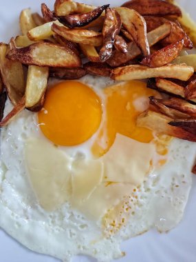 Lezzetli bir frittata menüsü. Yanında taze, güneşli, kızarmış patatesle birlikte yumurtalar. Tabakta canlı sarı sarılar ve mükemmel pişirilmiş beyazlar, konfor ve lezzetli bir ev yapımı kahvaltı veya brunch 'ın keyfi yer alıyor..