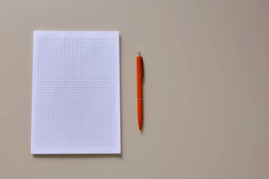 Masanın üzerinde bir defter ve kırmızı bir kalem var. Pastel gözlük. Yatay çerçeve.
