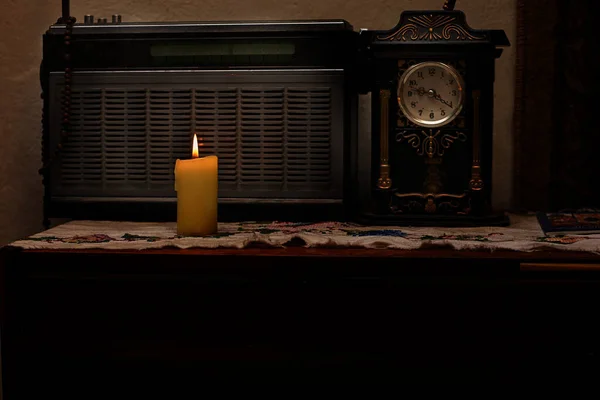 Mum yanıyordu. Eski bir radyo ve eski bir saatin arka planına karşı. Yaşlı insanların yalnızlığını sembolize ediyor. Alçakgönüllülük. Yatay çerçeve.