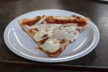 .Kafedeki masanın üzerinde bir dilim pizza var. Ne? O, üçgen şeklinde. Beyaz bir tabakta. Yatay çerçeve.