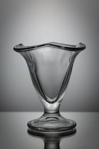 Masanın üzerinde bir dondurma bardağı var. Beyaz bir arka planda. Dikey çerçeve.