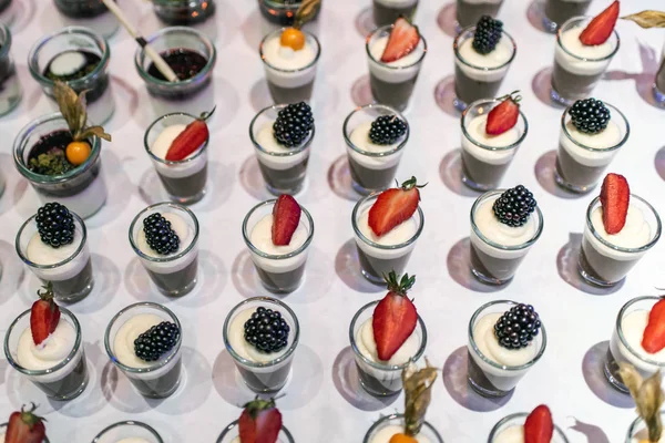 Gros plan de nombreux bocal à dessert ramé sur la table buffet avec gelée de fruits frais et crème — Photo