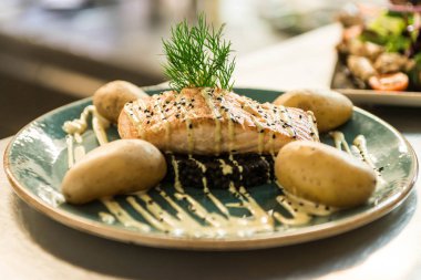 siyah bulgur ve pişmiş patates yemek için düzenlenmiş bir plaka üzerinde yerleştirilen ızgara somon
