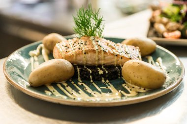 siyah bulgur ve pişmiş patates yemek için düzenlenmiş bir plaka üzerinde yerleştirilen ızgara somon