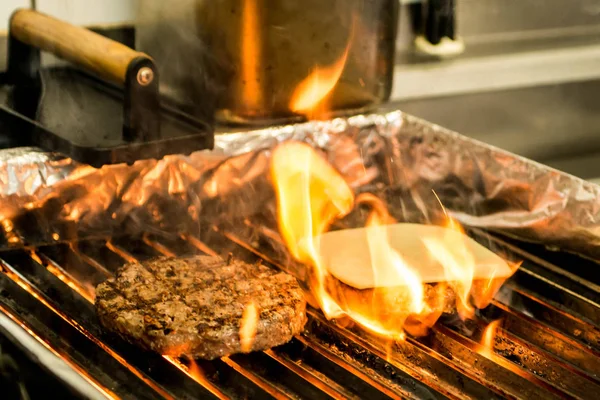 Hamburger beef patty grilled meat and cheese on a barbecue grill fire — Stock Photo, Image