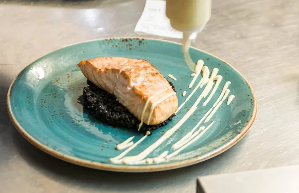 ızgara somon ile siyah bulgur aşçı ile soyunma kapsayan bir tabağa yerleştirilmiş