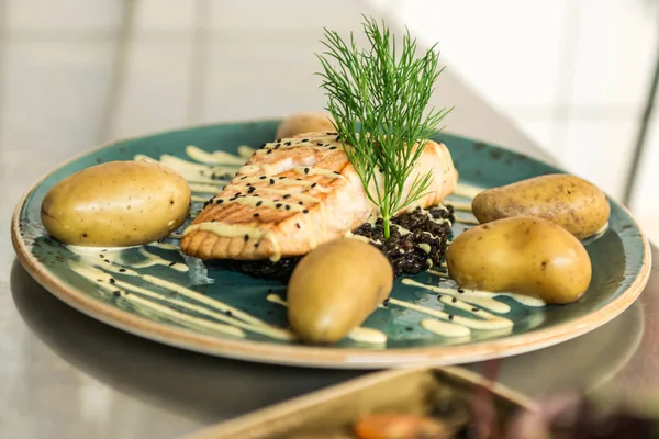 siyah bulgur ve pişmiş patates yemek için düzenlenmiş bir plaka üzerinde yerleştirilen ızgara somon