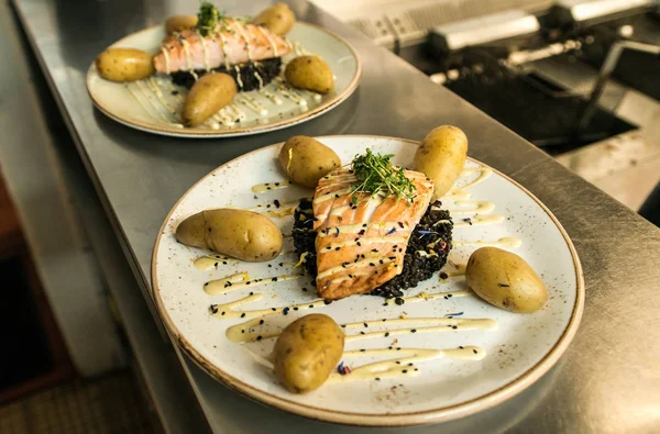 siyah bulgur ve pişmiş patates yemek için düzenlenmiş bir plaka üzerinde yerleştirilen ızgara somon