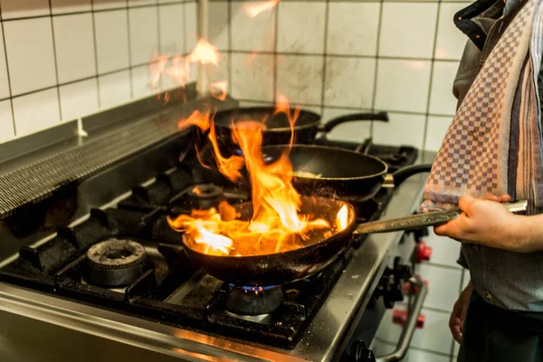 Restaurant Chef cooking with flame in a frying pan on a kitchen stove — Stock Photo, Image
