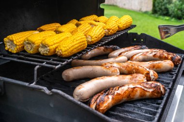 Taze sosis ızgara mısır yakın çekim ile pişirilir. Arka plan kömür ile yapılan sosis