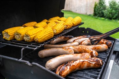 Taze sosis ızgara mısır yakın çekim ile pişirilir. Arka plan kömür ile yapılan sosis