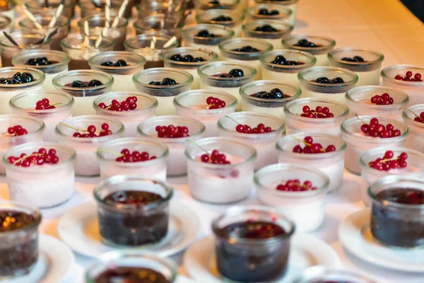 Closeup many dessert jar rowed up on buffet table with fresh fruits jelly and cream — Stock Photo, Image