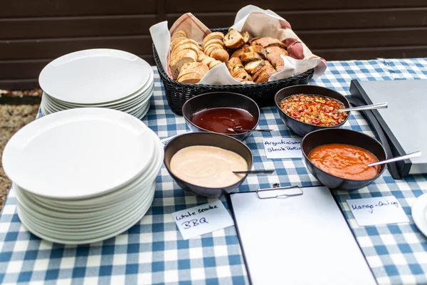 Various dip sauces on black bowls with white plates on dinner table setting — Stock Photo, Image