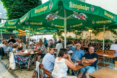Koblenz Germany -28.07.2018 Picture of people sitting in a typical German koenigsbacher beer garden in the town Koblenz clipart