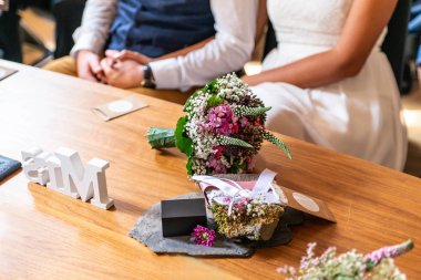 Bir buket çiçek ve evlilik çift arka planı ahşap yüzeyde güzel alyans yalan