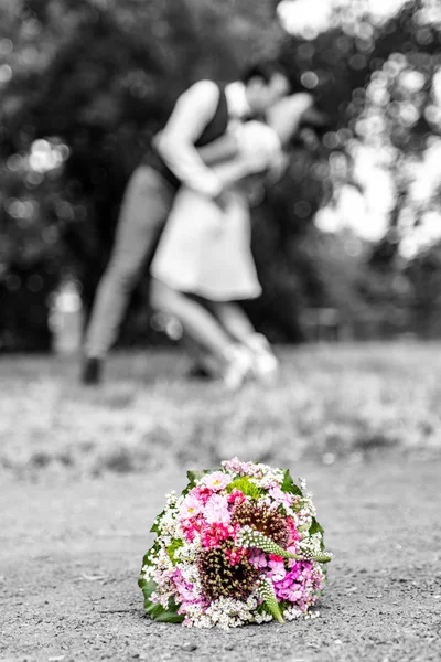 Wedding bouquet in front of newlyweds couple background, kissing Shallow depth bokeh — Stock Photo, Image