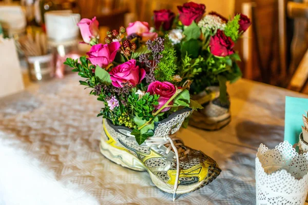 Старые красочные спортивные туфли, используемые в качестве вазы цветочный горшок для украшения свадьбы — стоковое фото