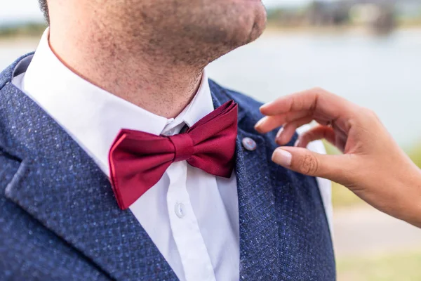 Невеста помогает жениху настроить тянуть красный галстук-бабочку — стоковое фото
