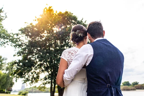 Back view of romantic couple of bride and groom hand in hand on at sunset