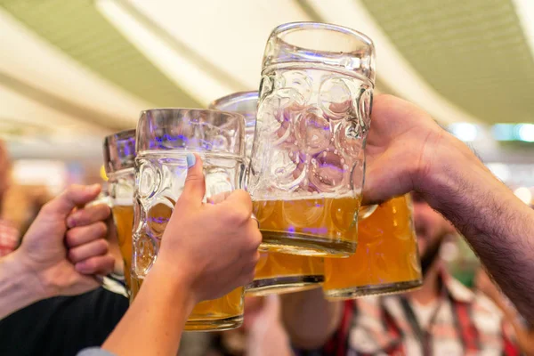 Un grupo de jóvenes Amigos brindando con vasos de cerveza en el Oktoberfest germany Soft focus. DOF poco profundo — Foto de Stock