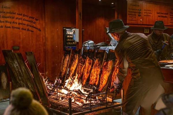 Bonn Germany 17.12.2017 delicious flamed Salmon is smoked on open fire at Christmas market — Stock Image Bonn Germany 17.12.2017 delicious flamed Salmon is smoked on open fire at Christmas market Stock Photo