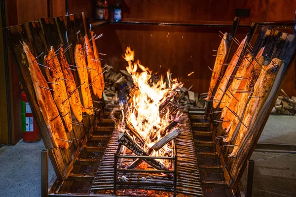 Delicious flamed Salmon is smoked on open fire at Christmas market — Stock Image Delicious flamed Salmon is smoked on open fire at Christmas market Royalty Free Stock Photos