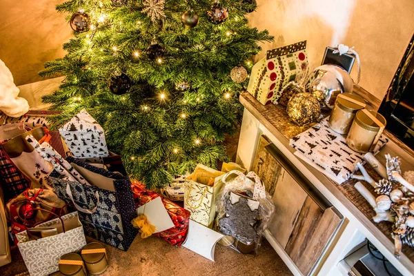 Pequeñas cajas de regalo hechas a mano en brillante colorido árbol de Navidad noche configuración celebración de fondo — Foto de Stock