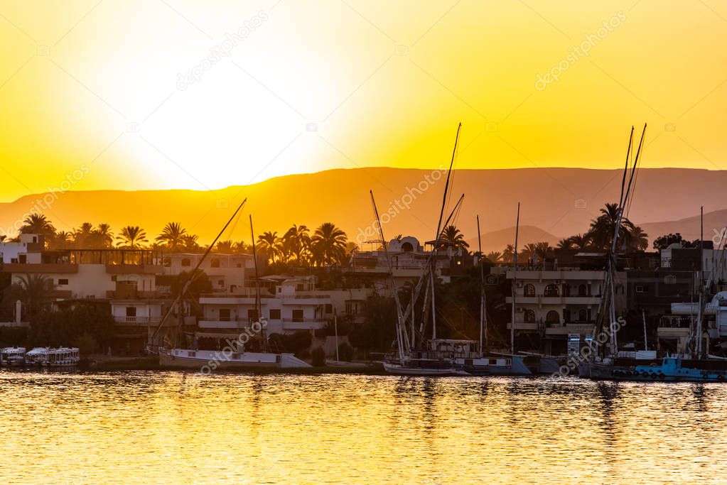 View of the Nile river with sailboats at golden colorful sunset in Luxor, Egypt