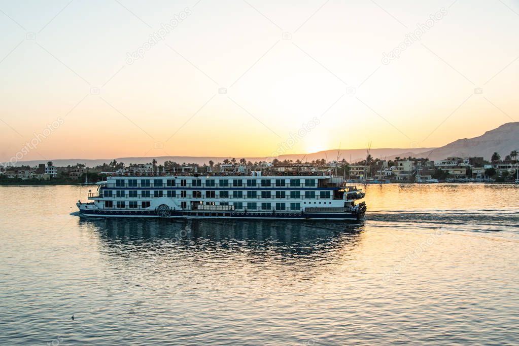 View of the Nile river with sailboats at golden colorful sunset in Luxor, Egypt