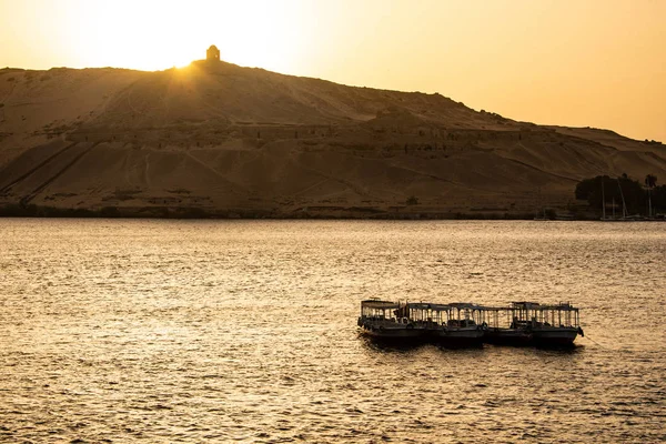 Západ slunce Nilu Asuánu a na západním břehu s hrobek staré říše Qubbet el-Hawa - Dome větrů na vrcholu kopce — Stock fotografie