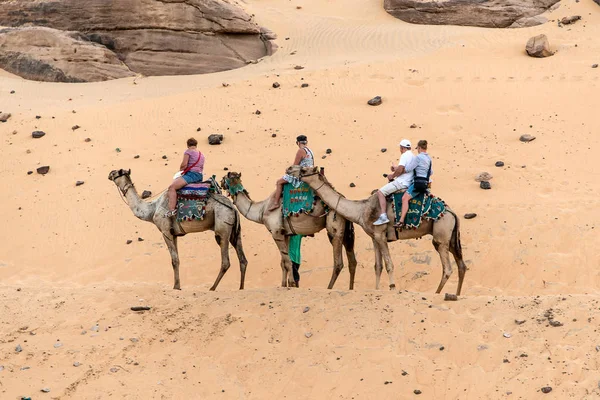 ASWAN, EGITTO 18.05.2018 Turisti a bordo di un tour in cammello nel villaggio nubiano sulla riva occidentale del fiume Nilo nella regione di Assuan — Foto Stock