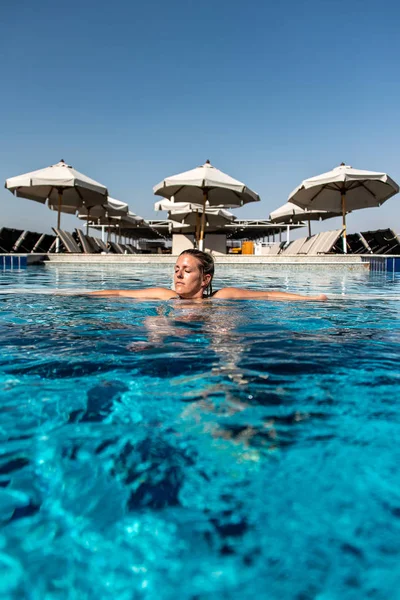 Junge schöne Frau sonnt sich im Schwimmbad bei luxuriösem Blick auf Sonnenschirm in Ägypten Luxus — Stockfoto