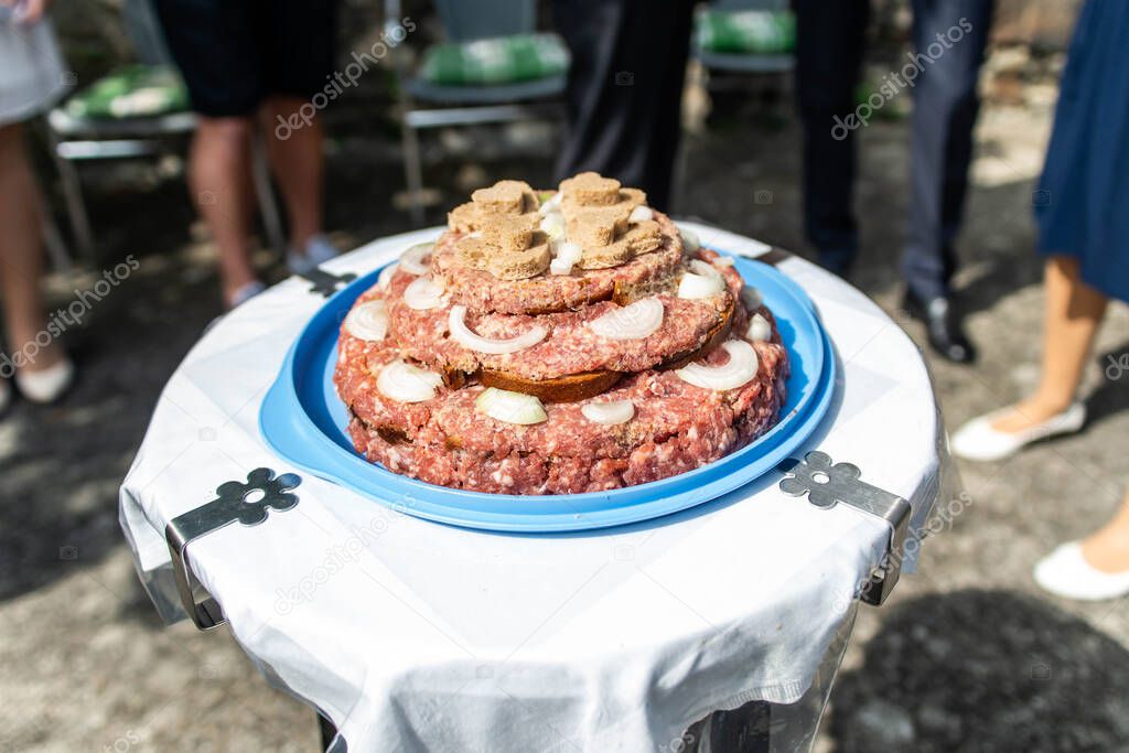 Wedding Cake raw ground pork cuisine burgers on tray with onion, rosemary and bread served on a wedding close-up