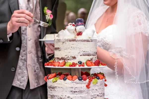新郎新婦の結婚おいしいフルーティーなウェディングケーキをカラフルな果物で切る — ストック写真