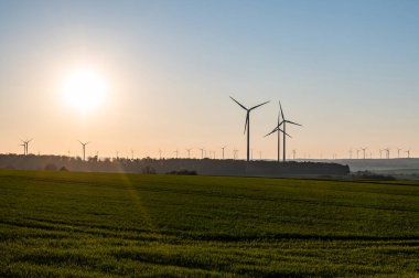 Rüzgâr türbinlerinin siyah silueti enerji jeneratörü Almanya 'da bir rüzgar çiftliğinde gün batımında