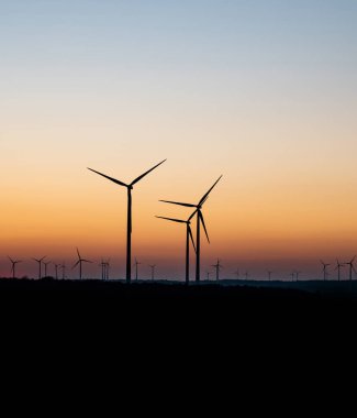 Rüzgâr türbinlerinin siyah silueti enerji jeneratörü Almanya 'da bir rüzgar çiftliğinde gün batımında
