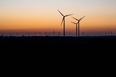 Rüzgâr türbinlerinin siyah silueti enerji jeneratörü Almanya 'da bir rüzgar çiftliğinde gün batımında
