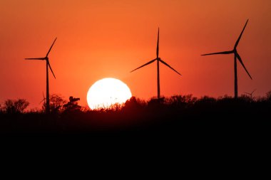 Rüzgâr türbinlerinin siyah silueti enerji jeneratörü Almanya 'da bir rüzgar çiftliğinde gün batımında