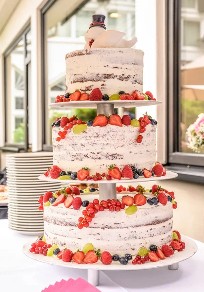 beautiful delicious Wedding cake in many tiers with fresh wild berries and fruits