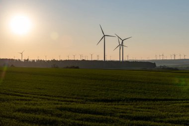 Rüzgâr türbinlerinin siyah silueti enerji jeneratörü Almanya 'da bir rüzgar çiftliğinde gün batımında